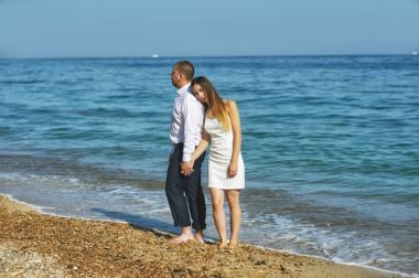 Gelin ve damat ayakta kol kola sahilde 