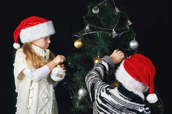 Kinderen versieren de kerstboom op de kamer. — Stockfoto