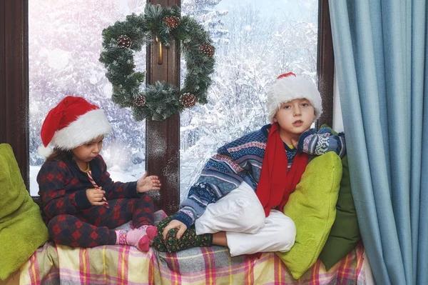 Kinderen zitten bij het raam in de winter — Stockfoto