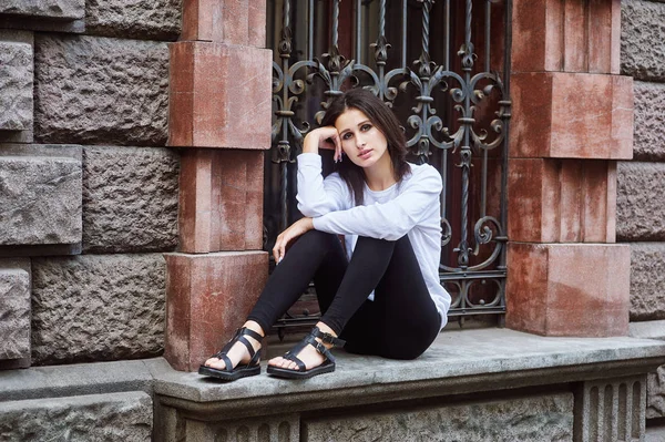 Young woman in casual clothes posing on a city street .The concept of easy casual wear .