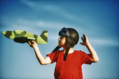 uçak ahşap bir modeli ile oynayan bir çocuk. Çocuk deri kask giymiş ve koruyucu gözlük. Pilot olmak çocukluk hayalleri