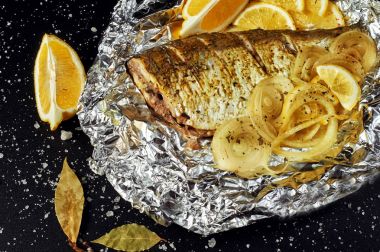 Fırında Balık folyo karanlık bir arka plan üzerinde. Üstten Görünüm