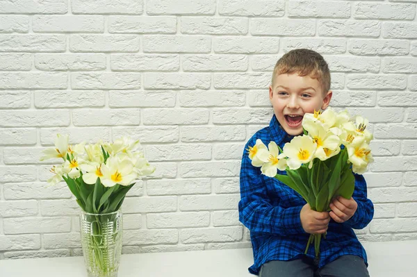 The boy at home holds a bouquet of flowers . Gift for mom