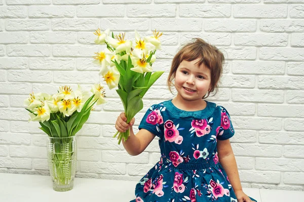 Beautiful little girl with a bouquet of flowers . Gift for mom