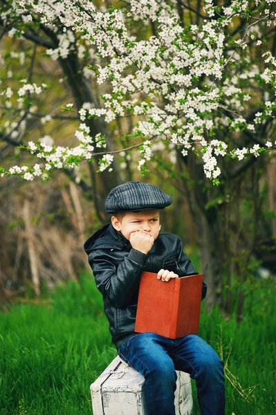 Jongen Lente Bloeiende Tuin Met Een Boek Zijn Handen — Stockfoto