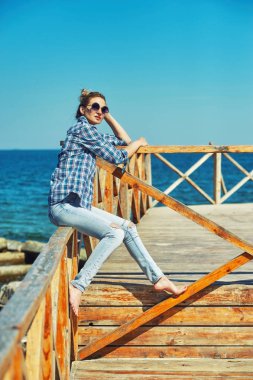 Sahilde genç bir kadın portresi. Deniz kıyısı üzerinde oturan kız