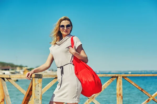 Portrait of a young woman at sea with a bag.The concept of summer vacation