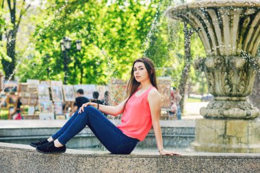 Güzel bir genç kız, model bir Avrupa şehri sokak üzerinde poz portresi. Kız kot pantolon ve bluz giymiş. Kadın moda kavramı.