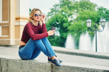 Kahve sokaklarda olan kadın. Kot pantolon ve bordo kazak şık genç kadın