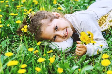 Dandelions olan küçük kız. Çimenlerin üzerinde kız