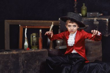 Karanlık arka planda vampir gibi giyinmiş bir çocuğun portresi. Cadılar Bayramı partisi.