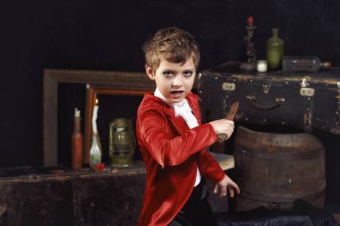 Karanlık arka planda vampir gibi giyinmiş bir çocuğun portresi. Cadılar Bayramı partisi.