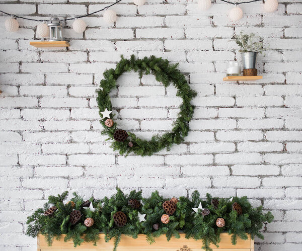 round elegant Christmas wreath hanging on white brick wall