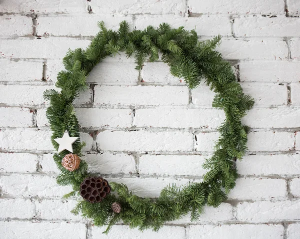 Rodada elegante grinalda de Natal pendurado na parede de tijolo branco — Fotografia de Stock