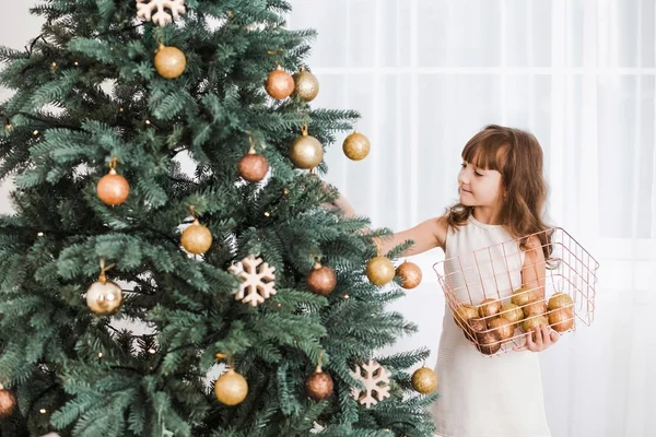 Petite fille décore arbre de Noël vert énorme — Photo