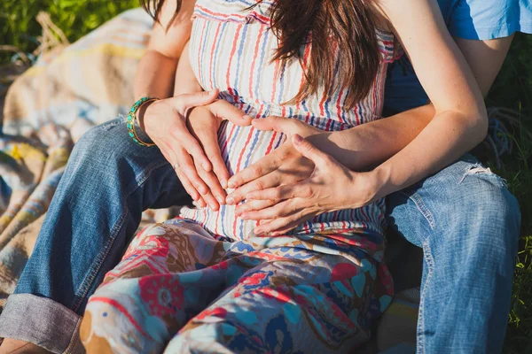 pregnant woman and her husband hugging beautiful round big belly with hands