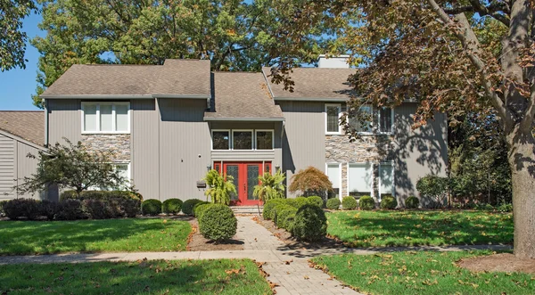 Серый современный дом с красной дверью и каменными акцентами — стоковое фото