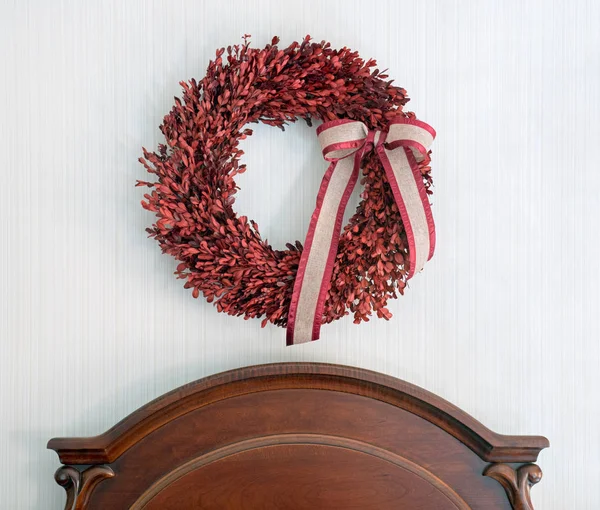 Couronne de buis rouge au-dessus de la tête de lit en bois — Photo