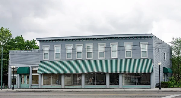 Gamla, historiska företag byggnad med grön randig markis — Stockfoto