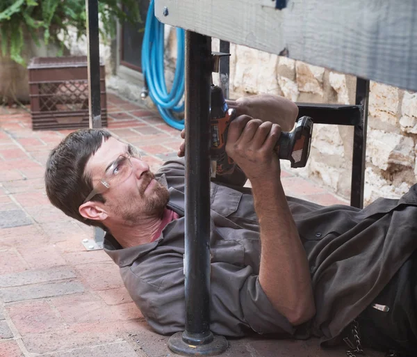 Agujero de perforación del trabajador en lugar incómodo — Foto de Stock