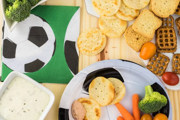 Party table for soccer game with variety of snacks and dips.