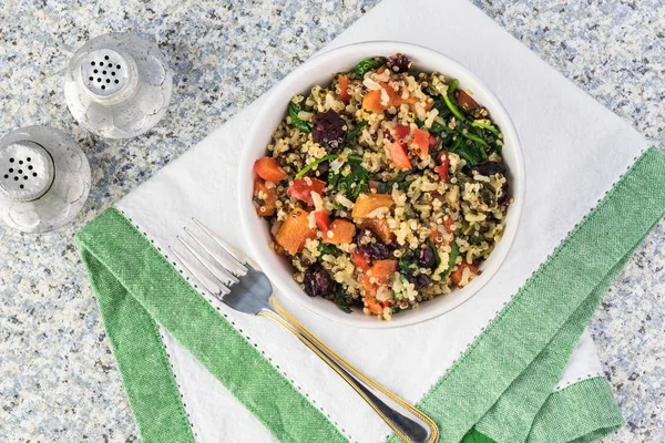 Cooked spinach quinoa brown rice with vegetables and berries.