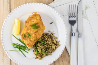 Kızarmış morina balığını ve Akdeniz usulü kinoayı beyaz tabakta yakın plan yap..