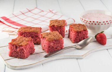 Kesme tahtasının üzerinde çilekli pasta dilimleri ve çilekli şekerleme ile kase..