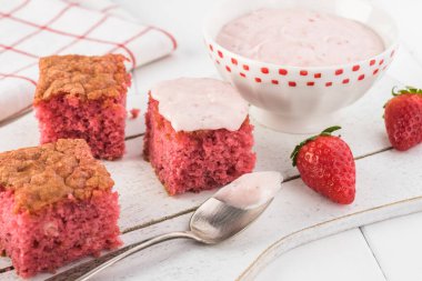 Kesme tahtasının üzerinde çilekli pasta dilimleri ve çilekli şekerleme ile kase..