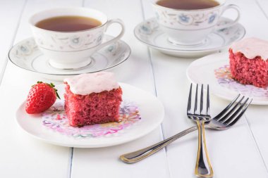 Kesilmiş çilekli pastayı bir tabakta ve bir fincan çayda kapat..
