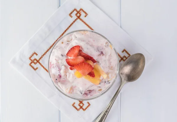 Bowl of frozen fruit salad decorated with fresh fruits.