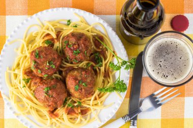 Marinara soslu spagetti ve köfte ile tabak ve bir bardak bira..