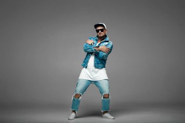 stüdyoda gri bir arka plan üzerinde kap ve kot elbiseli adam