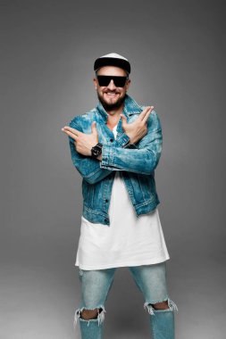 stüdyoda gri bir arka plan üzerinde kap ve kot elbiseli adam