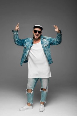 stüdyoda gri bir arka plan üzerinde kap ve kot elbiseli adam