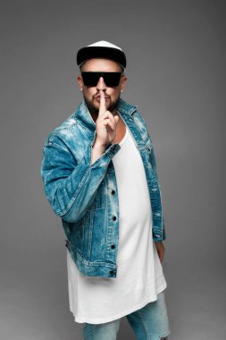 stüdyoda gri bir arka plan üzerinde kap ve kot elbiseli adam