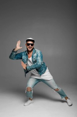 stüdyoda gri bir arka plan üzerinde kap ve kot elbiseli adam