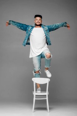 stüdyoda gri bir arka plan üzerinde kap ve kot elbiseli adam