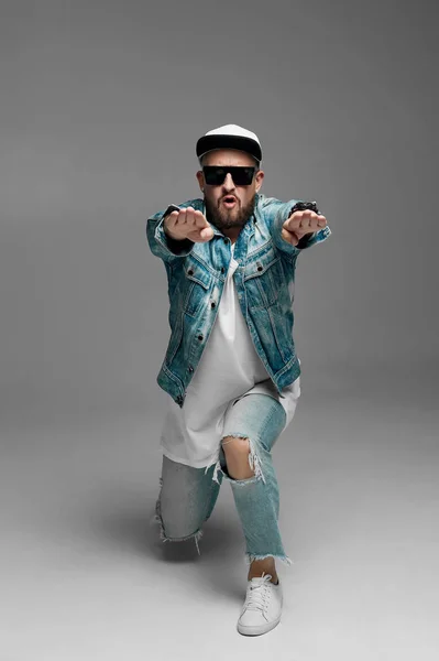 stüdyoda gri bir arka plan üzerinde kap ve kot elbiseli adam