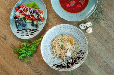 Carbonara salatası ve turkuaz tabaklar masanın üzerinde duruyor.