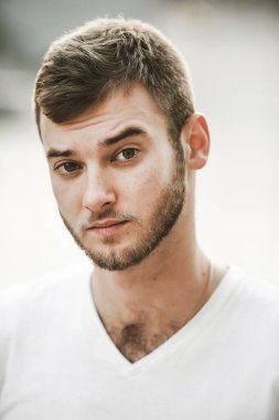 Çeşitli duyguları olan güler yüzlü arkadaş canlısı bir adam beyaz tişörtlü ve elinde saati olan bir adam.;