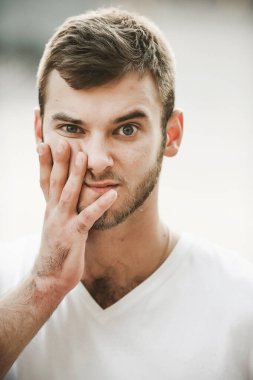 Çeşitli duyguları olan güler yüzlü arkadaş canlısı bir adam beyaz tişörtlü ve elinde saati olan bir adam.;