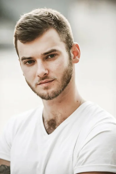 Çeşitli duyguları olan güler yüzlü arkadaş canlısı bir adam beyaz tişörtlü ve elinde saati olan bir adam.;