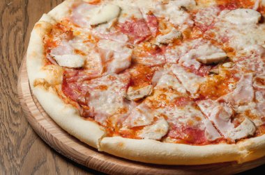 Tahta bir tepside pizza, ahşap bir masada duruyor.