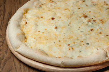Tahta bir tepside pizza, ahşap bir masada duruyor.