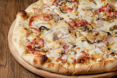 Tahta bir tepside pizza, ahşap bir masada duruyor.