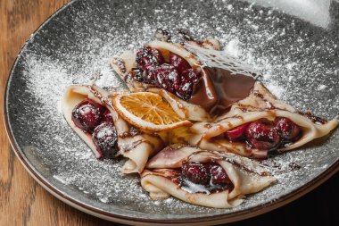 Krep ve vişneli krep üzerine şeker serpiştirilmiş.