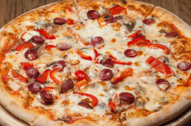 Tahta bir tepside pizza, ahşap bir masada duruyor.