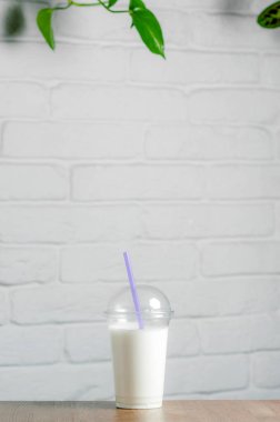Milkshake beyaz bir duvara karşı bir masada duruyor.