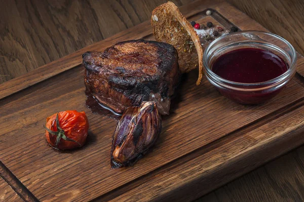 juicy steak with sauce on a board stands on a wooden table